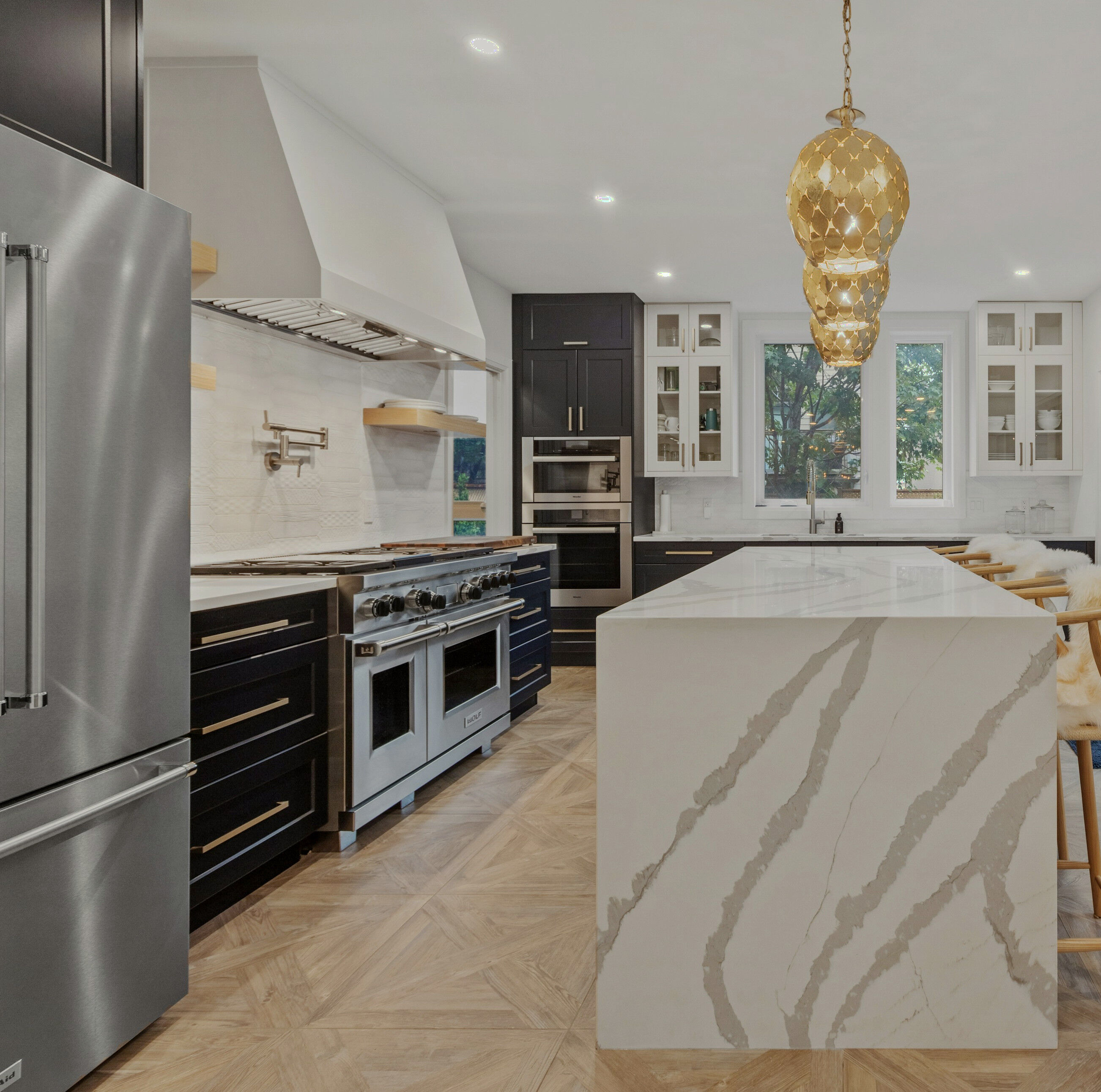 A luxury kitchen with a marble waterfall island and brass pendant lighting
